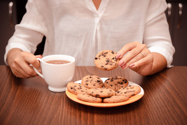 Woman enjoy pause in work with cookie and tea. Simple pleasures of food - Photo, Image