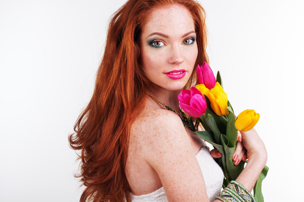 Beautiful redheaded girl is holding tulips - Foto, Imagen