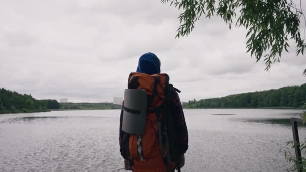 der Reisende steht auf dem Hintergrund des Flusses und der Stadt mit Sportgeräten Rückansicht - Filmmaterial, Video