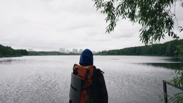 le voyageur se tient sur le fond de la rivière et de la ville avec équipement sportif vue arrière - Séquence, vidéo