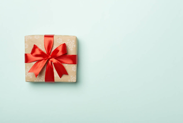 Geschenkkarton mit roter Schleife auf farbigem Hintergrund, Ansicht von oben. - Foto, Bild