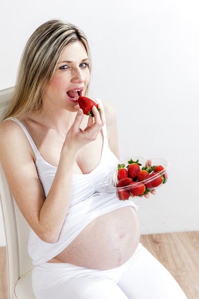 イチゴを食べて妊娠中の女性の肖像画 - 写真・画像