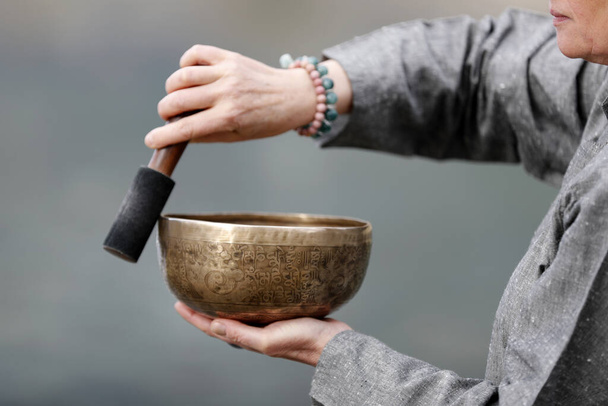 Tibetische Schale wird in der Klangtherapie, Meditation und Yoga verwendet. Frau, die eine Klangschale zur Klangtherapie in der Atmosphäre zur Heilung, Meditation und Entspannung praktiziert. Frankreich.  - Foto, Bild