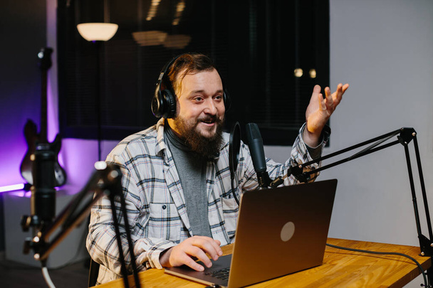 Un bloguero en línea habla en un micrófono durante una transmisión. Presentador de radio en el estudio durante la emisión. - Foto, Imagen