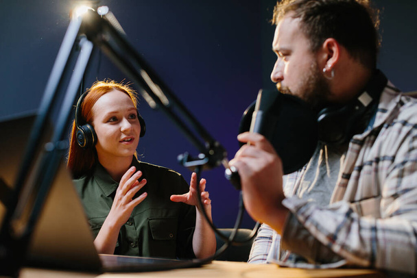 Ο άνθρωπος έχει συνομιλία με τη γυναίκα στο διαδίκτυο που μεταδίδεται χρησιμοποιώντας επαγγελματικό μικρόφωνο και μίξερ ήχου. Online ραδιοφωνικός σταθμός υποδοχής καταγραφή podcast συνέντευξη επισκέπτη σε αργά το βράδυ talk show. - Φωτογραφία, εικόνα