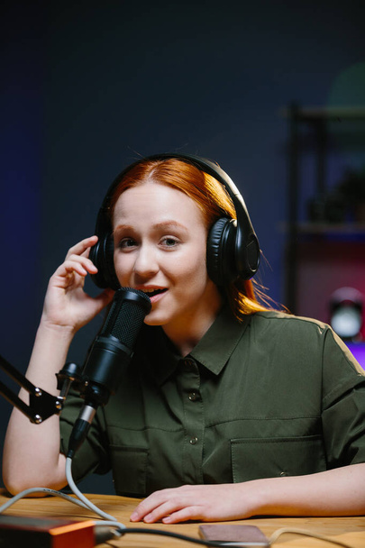 La presentadora habla en el micrófono durante la transmisión en la radio. - Foto, Imagen