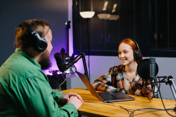A podcast host and a guest have fun chatting during a live online broadcast in a home studio. - Zdjęcie, obraz