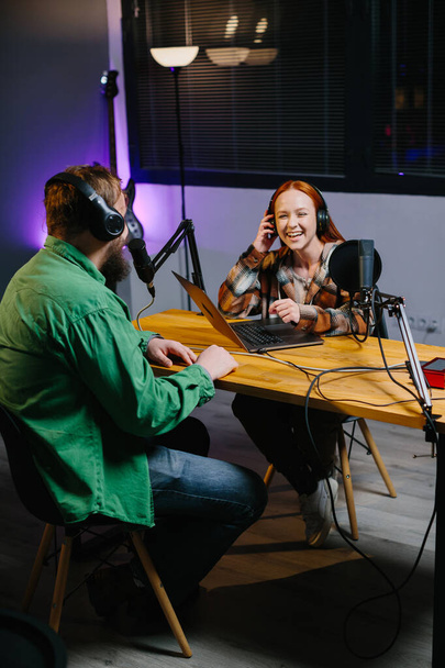 Um anfitrião de podcast e um convidado se divertem conversando durante uma transmissão online ao vivo em um estúdio em casa. - Foto, Imagem