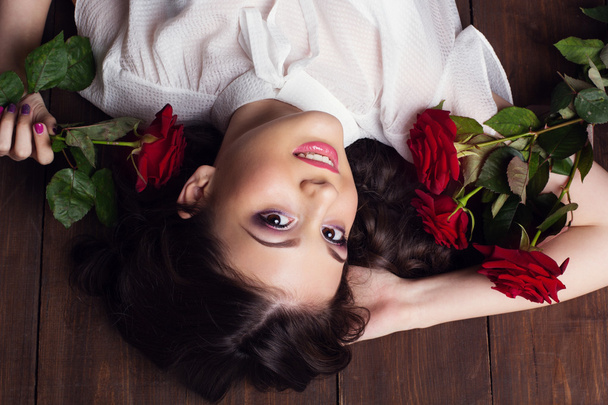 Pretty teenager girl lying with red roses - Foto, imagen