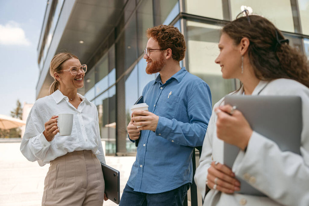 Veselí obchodníci mluví a smějí se během přestávky mimo kancelář - Fotografie, Obrázek