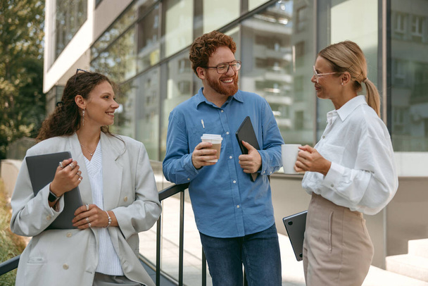 Iloiset liikemiehet puhuvat ja nauravat tauon aikana toimiston ulkopuolella - Valokuva, kuva