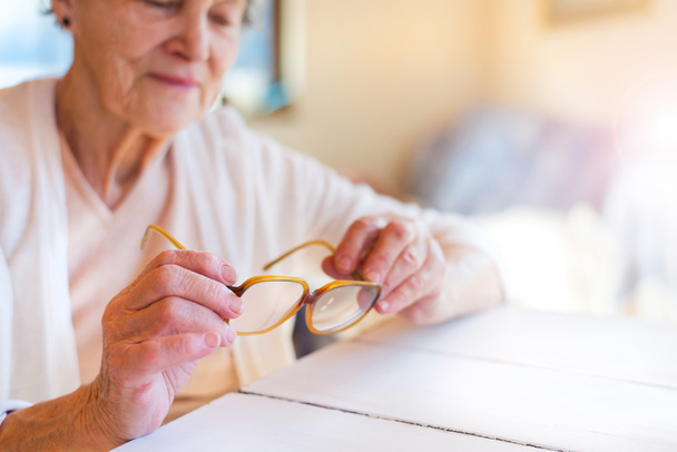 Senior woman holding glasses - Fotoğraf, Görsel