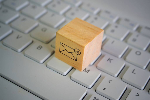 Wooden cube with new email notification icon on top of keyboard. Communication and technology concept - Photo, Image
