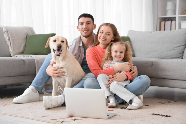 Щаслива сім'я з собакою Лабрадором і ноутбуком вдома - Фото, зображення