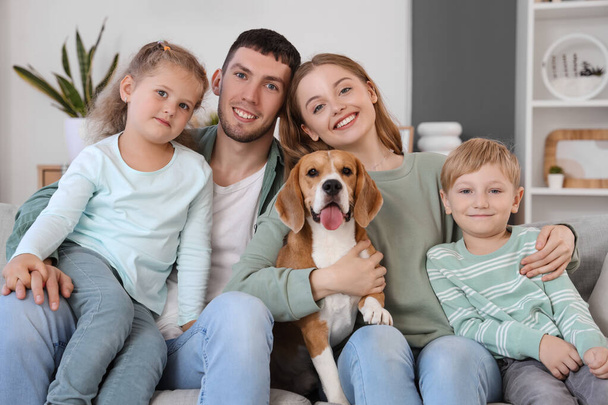 Niños pequeños con sus padres y lindo perro Beagle sentado en el sofá en casa - Foto, imagen