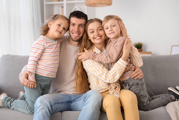 Glückliche kleine Kinder mit ihren Eltern, die sich zu Hause auf dem Sofa umarmen - Foto, Bild