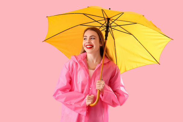 Bella donna elegante in impermeabile con ombrello su sfondo rosa - Foto, immagini