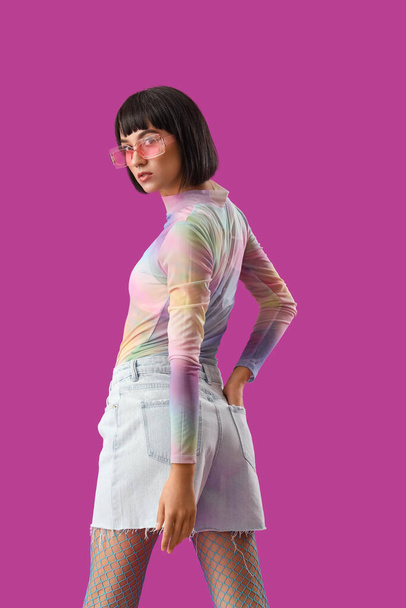 Piękna młoda stylowa kobieta w okularach przeciwsłonecznych na fioletowym tle - Zdjęcie, obraz