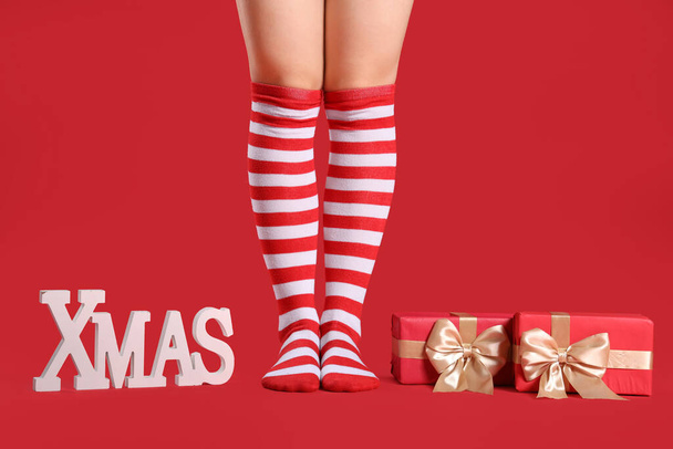 Noel çoraplı kadın hediye kutuları ve kırmızı arka planda XMAS sözcüğü. - Fotoğraf, Görsel
