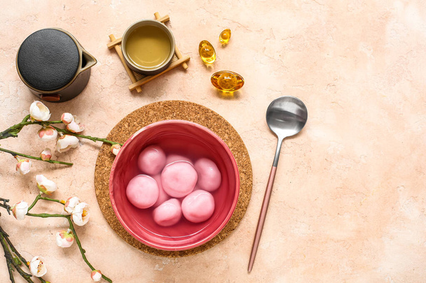 Egy tál tangyuan, tea, kínai dekoráció és sakura bézs alapon. Dongzhi Fesztivál - Fotó, kép