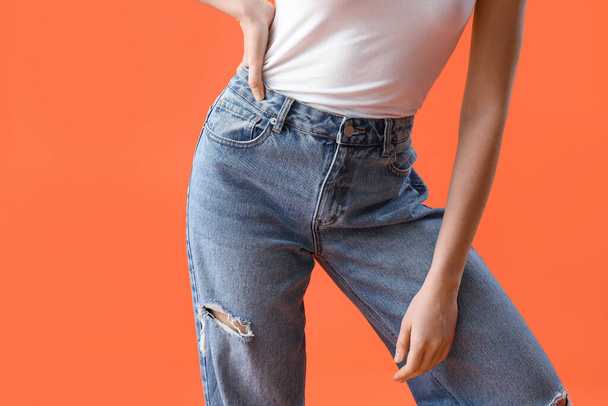 Mujer joven en jeans con estilo sobre fondo naranja, primer plano - Foto, imagen
