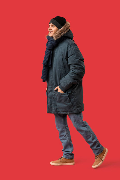 Fiatal férfi elegáns puffer kabát és sál piros háttér - Fotó, kép