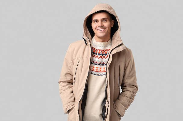 Young man in stylish puffer jacket on grey background - Фото, изображение