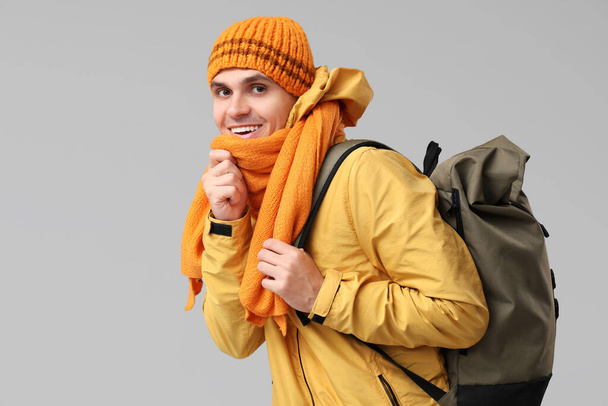 Młody mężczyzna w żółtej stylowej kurtce i szaliku z torbą na szarym tle - Zdjęcie, obraz