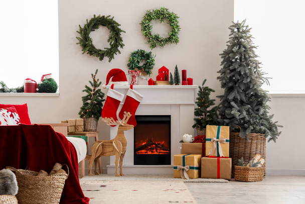 Interieur des festlichen Wohnzimmers mit Kamin, Geschenkschachteln, Weihnachtsbaum und Dekorationen - Foto, Bild
