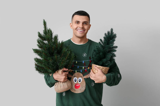 白い背景にクリスマスツリーを持つ若い男 - 写真・画像