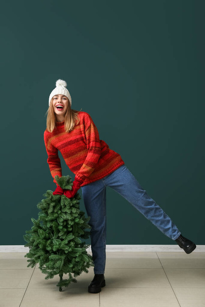 Mujer joven feliz con árbol de Navidad sobre fondo verde - Foto, Imagen