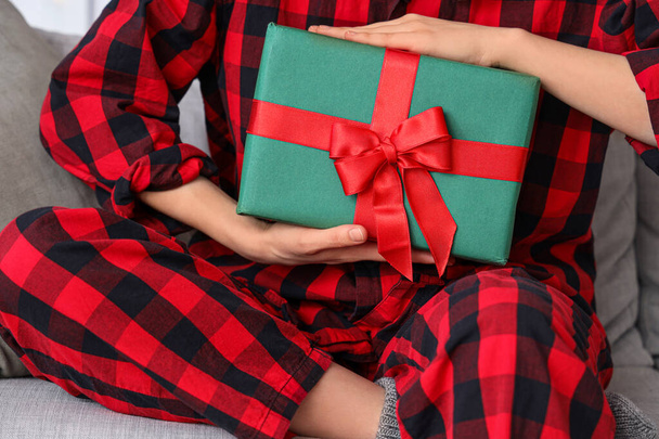 Joyeux jeune femme en pyjama avec cadeau de Noël assis à la maison, gros plan - Photo, image