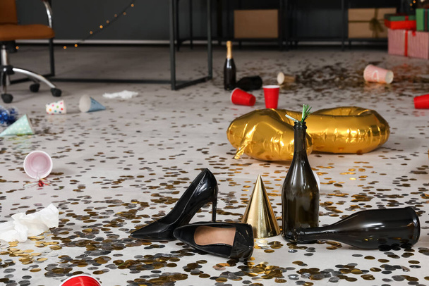 新年のパーティーの後の混乱したオフィスの床のびんそして confetti が付いているヒール,閉鎖 - 写真・画像