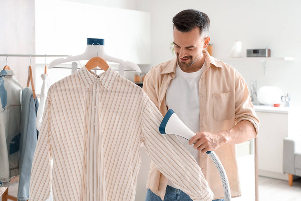 Hezký muž parní košile s moderním parníkem doma - Fotografie, Obrázek