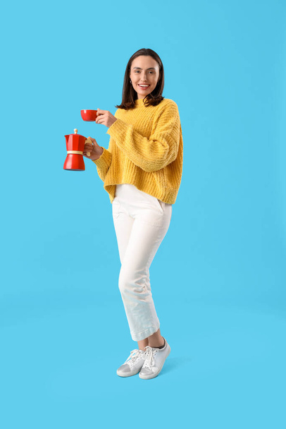 Jolie jeune femme avec machine à café geyser et tasse d'espresso sur fond bleu - Photo, image