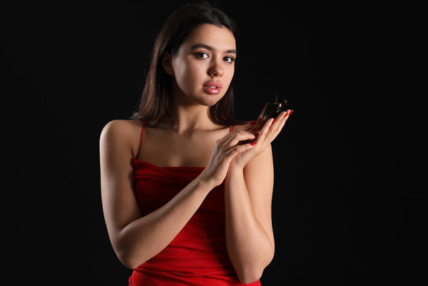 Attractive young woman with perfume on dark background - Photo, Image