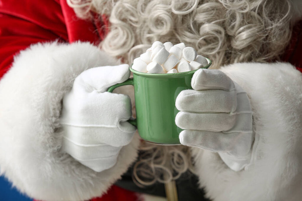 Santa Claus sosteniendo taza de sabrosa bebida de cacao con malvaviscos, primer plano - Foto, Imagen
