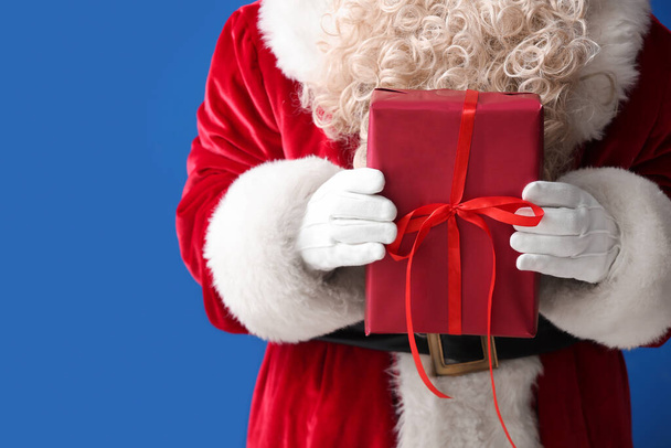 Papai Noel segurando caixa de presente no fundo azul, close-up - Foto, Imagem