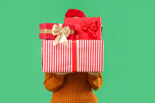 Young woman with Christmas gifts on green background - Photo, Image