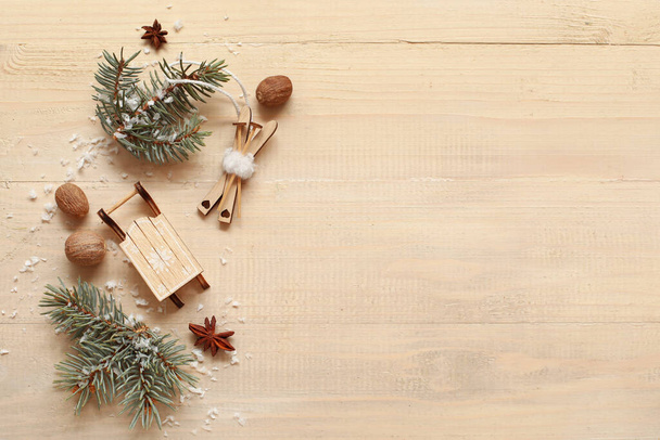 Wooden toys with snow, nuts and fir branches on light wooden background. Winter solstice concept - Photo, Image