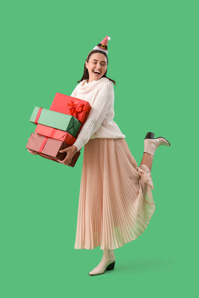 Giovane donna a Santa cappello con regali di Natale su sfondo verde - Foto, immagini