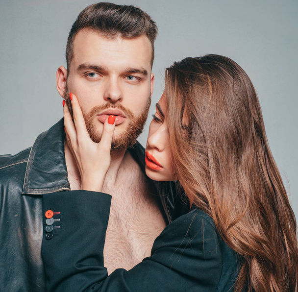 Passionate hug. Couple passionate people in love. Man brutal well groomed macho and attractive girl cuddling. Girlfriend passionate red lips and man leather jacket. She adores male brutal beard. - Fotoğraf, Görsel