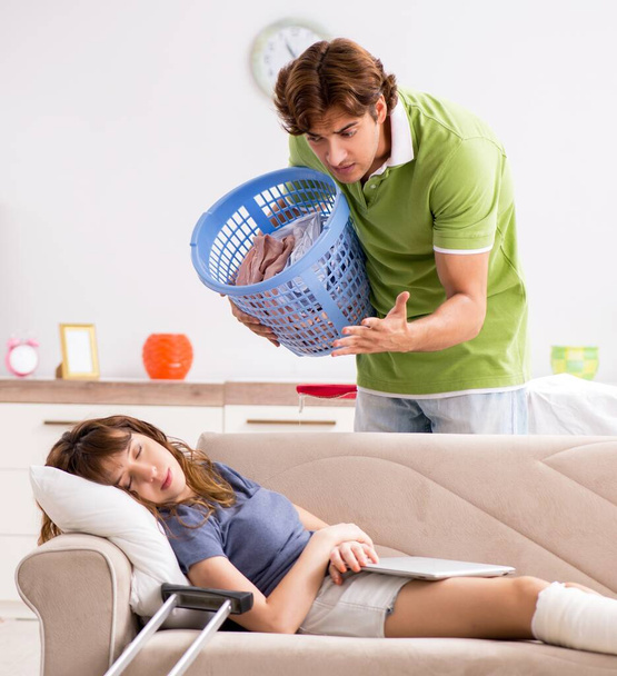 O marido ajudando a perna ferida esposa em tarefas domésticas - Foto, Imagem