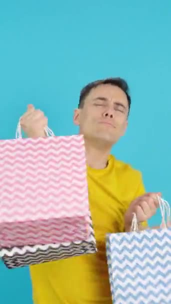 Videó a stúdióban kék háttérrel egy férfi táncol és mosolyog a bevásárló táskák. A keret üres, a férfi alulról jelenik meg, majd eltűnik az alján. - Felvétel, videó