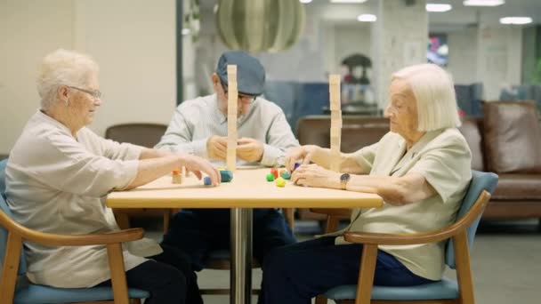 Video che si avvicina a tre anziani che giocano a giochi di abilità cerebrali in una casa di cura - Filmati, video