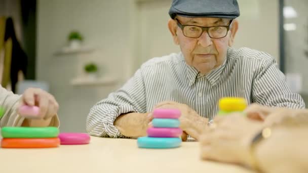 Video van een oudere man met baret op zoek naar camera met serieuze blik in een geriatrie - Video