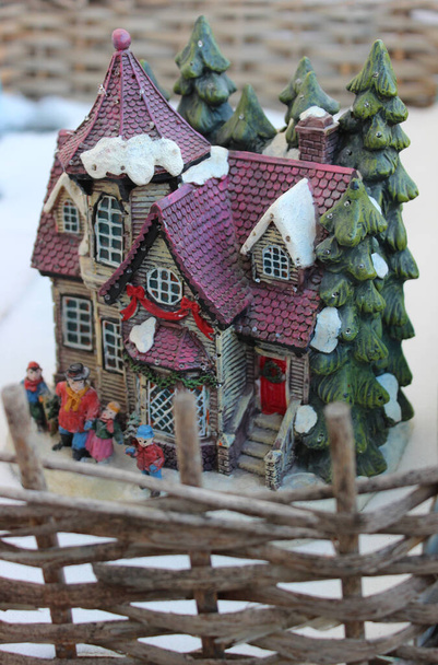 A játék dioráma a kis ház egy téli környezetben körülvéve egy wattle kerítés - Fotó, kép