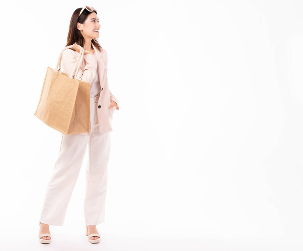 Jonge vrouw in pak en bril houden boodschappentas met aankopen geïsoleerd op witte achtergrond studio portret Winkel korting verkoop Jonge zakenvrouw kijken naar kopieerruimte met gelukkig en glimlach gezicht - Foto, afbeelding