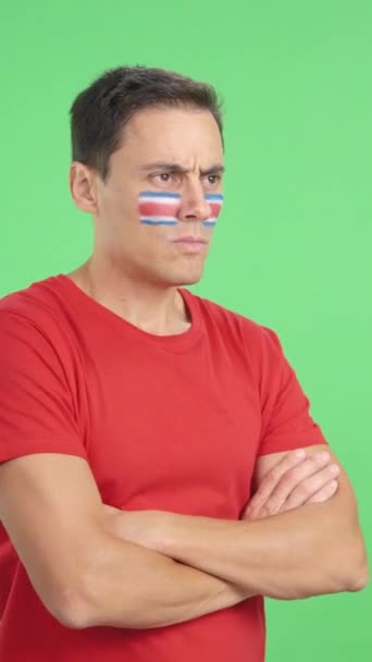 Yüzünde Kosta Rika bayrağı olan bir adamın ciddi bir ifadeyle yüzünü çevirdiği bir film stüdyosunda. - Video, Çekim