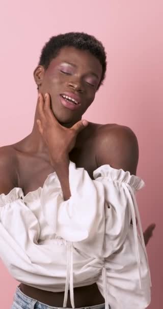 Κομψό αφρικανικό τρανσέξουαλ άτομο κάνει διαφορετικές στάσεις, ενώ στέκεται σε ένα απομονωμένο ροζ φόντο. - Πλάνα, βίντεο
